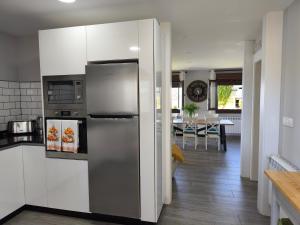 a kitchen with a stainless steel refrigerator and a dining room at Apartamentos Mareventus in Sanxenxo