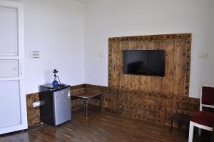 a room with a wooden wall with a flat screen tv at VELORA-DOODHPATHRi in Aphit