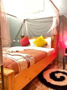 a bedroom with a wooden bed with colorful pillows at Kisoro Suits in Kisoro