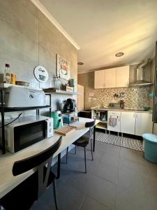 a kitchen with a table with a microwave on it at Fonte da Telha Beach Hostel in Costa da Caparica