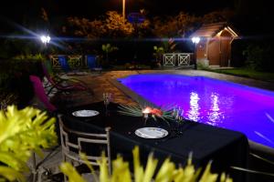 a table with plates on it next to a swimming pool at night at Bed and breakfast Riviere in Le Marin