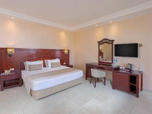 a bedroom with a bed and a desk and a television at Royal Brayka Beach Resort in Marsa Alam City