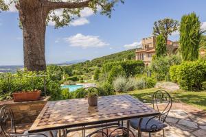 a patio with a table and chairs and a tree at La Vecchia Sassa in Montaione