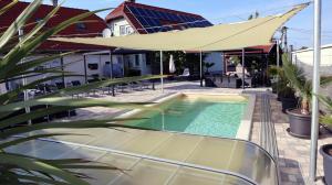 a swimming pool with an umbrella next to a house at Siófok apartman in Siófok