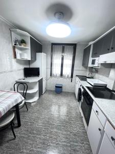 a kitchen with white cabinets and a sink and a table at Centrico tu hogar en Bilbao in Barakaldo