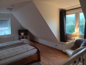 a bedroom with a bed and a chair and a window at Heringsmoewe in Tossens