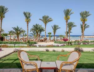 a table and chairs with a view of the beach and palm trees at Royal Brayka Beach Resort in Marsa Alam City