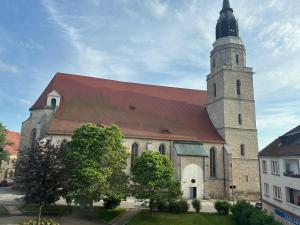 a large church with a tower and a red roof at Apartament24-Just in Center in Bolesławiec