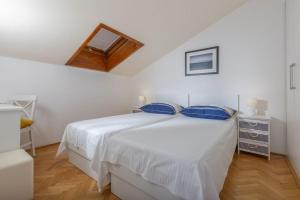 a white bedroom with a white bed with blue pillows at Apartment Amfora in Podgora