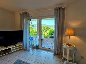 a living room with a television and a sliding glass door at Eifelglück in Heimbach
