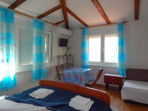 a bedroom with a bed and a table and two windows at Guest House Frane in Pag