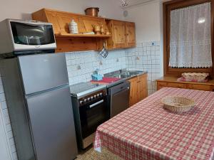 eine Küche mit Kühlschrank, Spüle und Tisch in der Unterkunft CasaColdai in Alleghe