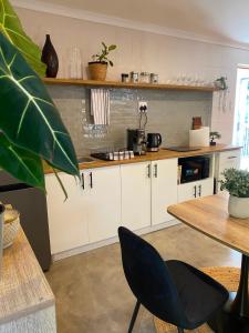 a kitchen with white cabinets and a table at The Cabernet Cottage - One Bedroom in Table View