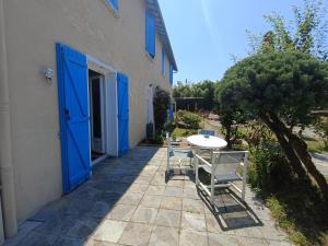 a patio with a table and chairs and a blue door at Maison Éléphantaisie in Salies-de-Béarn