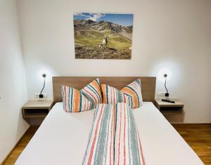 a bedroom with a white bed with two lamps at Berghoamat Nauders in Nauders