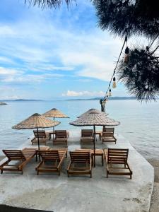 a group of chairs and umbrellas on the beach at Denizevi Karvunyi in Marmara Adasi