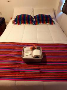 a suitcase sitting on a bed with a colorful blanket at VittoriaHouse in Ollantaytambo +3 photos