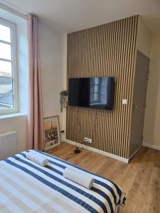 a bedroom with a bed and a flat screen tv on a wall at Studio moderne en hyper-centre de Vendôme in Vendôme