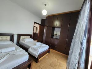 a bedroom with two beds and wooden cabinets at Mihal Suites in Sarandë