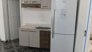 a kitchen with a white refrigerator and a wooden cabinet at Casa da Floresta in Vitória