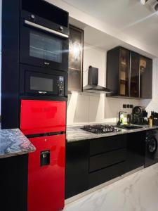 a kitchen with red and black cabinets and a stove at Fa Apartment in Lekki +29 photos