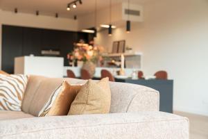 a couch with pillows sitting in a living room at The Strand Agency - June in Cadzand-Bad