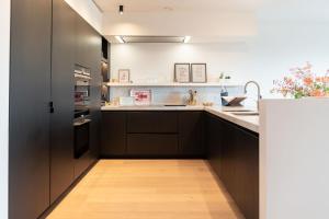 a kitchen with dark brown cabinets and a sink at The Strand Agency - June in Cadzand-Bad