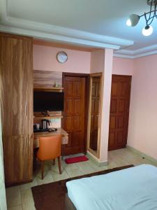 a bedroom with a bed and a desk and a table at New Land Sarl in Douala