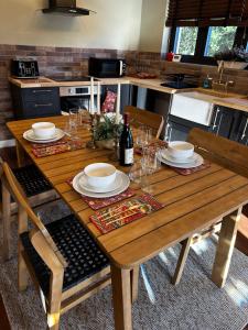 a wooden table with plates and wine glasses on it at Tree Top & Bluebell Cottages in Grange Road Station