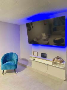 a living room with a large tv and a blue chair at Modern 4BR Oasis in Bayamón