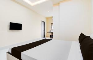 a bedroom with a bed with a tv on the wall at Townhouse Oak Howrah Junction Kolkata in Kolkata +15 photos