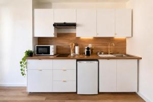 a kitchen with white cabinets and a sink at Terre d'Oasis - HyperCentre in Besançon
