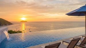 a swimming pool with a sunset over the ocean at Buzios Mar Hotel in Búzios
