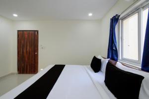 a bedroom with a bed with black and white pillows at Hotel O Sree Nirvi in Ameerpet