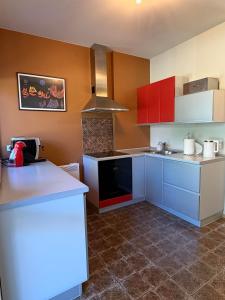 a kitchen with red and blue cabinets and a counter at Poilsis Urbo Nidoje in Nida