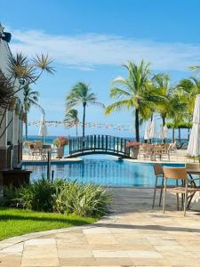 a pool with tables and chairs and palm trees at WaiWai Residence Cumbuco in Caucaia