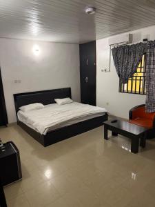 a bedroom with a bed and a chair and a table at Epa's Place in Awoyaya