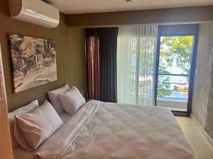 a bedroom with a large white bed with a window at Denizevi Karvunyi in Marmara Adasi