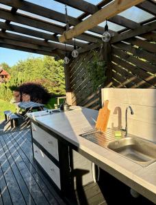 an outdoor kitchen with a sink and a wooden pergola at Šķilas in Pērkone