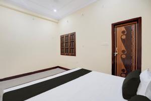 a bedroom with a white bed and a wooden door at Hotel O Relax Inn in Lucknow