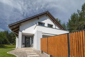 a white house with a wooden fence at Willa Vivaldi - Family & Friends - Sauna, Balia in Grzybowo