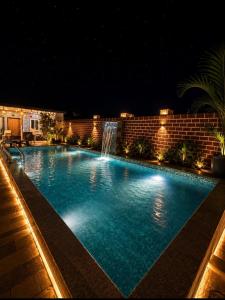 a swimming pool at night with a waterfall at Aanadam Resort in Jaipur