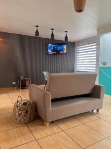 a living room with a couch and a tv on a wall at La Terraza Orgánica in Cartago