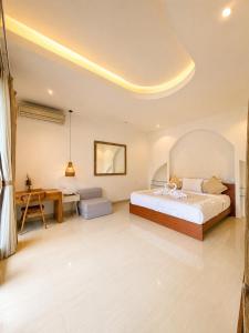 a bedroom with a large bed and a desk at Asania Villa in Uluwatu