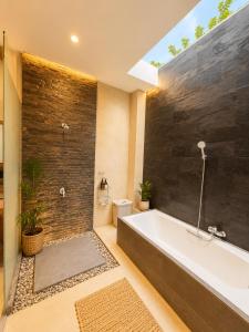 a bathroom with a large bath tub and a window at Asania Villa in Uluwatu