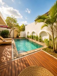 a swimming pool in a backyard with a wooden deck at Asania Villa in Uluwatu +9 photos