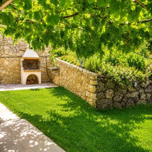 a garden with a stone wall and a fireplace at Endless Green Villa in Argostoli