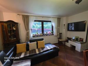 a living room with a black leather couch and a window at Pensiunea Daria Putna in Putna