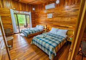a bedroom with two beds in a log cabin at Jacaranda House, rustic, Private Pool in Talamanca +10 photos