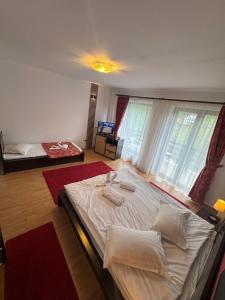 a bedroom with a large bed in a room with windows at Hotel boutique Garden Resort by Brancoveanu in Moieciu de Jos +97 photos